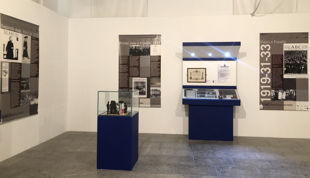 Exhibition dedicated to Maria Sklodowska-Curie, showing informational panels about her trips to Spain and historical objects in a display case.