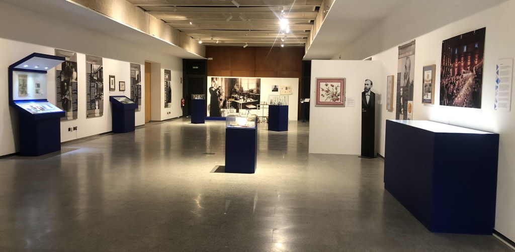 Exhibition hall with panels and display cases dedicated to Maria Sklodowska-Curie, showing documents, objects, and photographs about her life and scientific career.