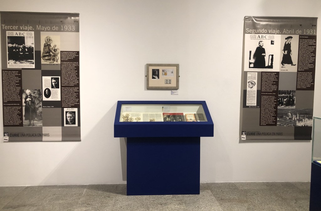 Exhibition about Maria Sklodowska-Curie with informational panels and display cases showing documents, photographs, and objects related to her trips to Spain in 1931 and 1933.