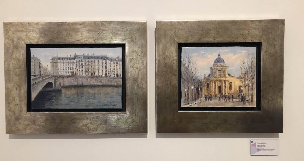 Two framed paintings depicting scenes of Paris: on the left, a bridge over a river with buildings in the distance, and on the right, a domed building surrounded by trees and people walking.