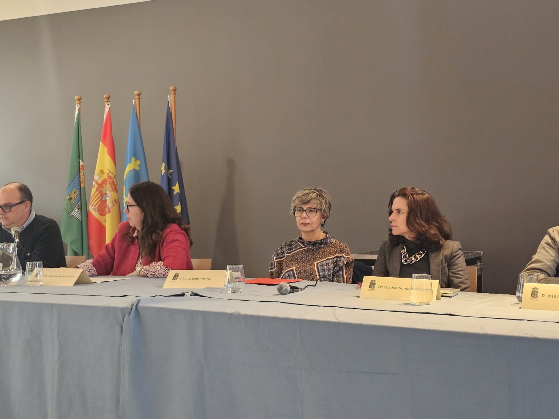 Round table with several speakers at the Arnao Mine Museum, during an event about the figure of Santiago Ramón y Cajal, with flags visible in the background.