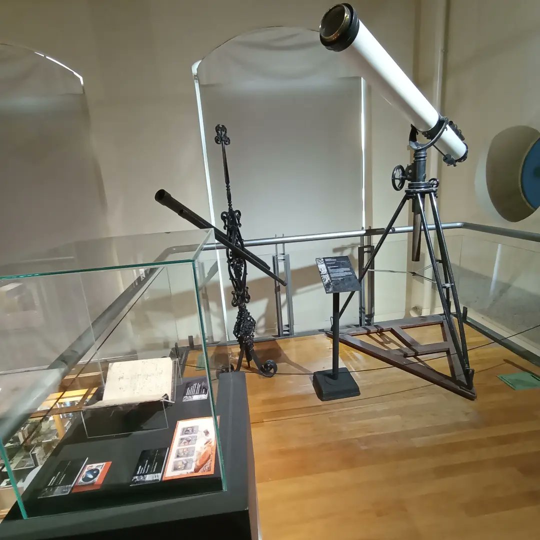 Exhibición de un telescopio antiguo y un microscopio en un museo, representando la conexión entre la historia de la ciencia y la exploración espacial.