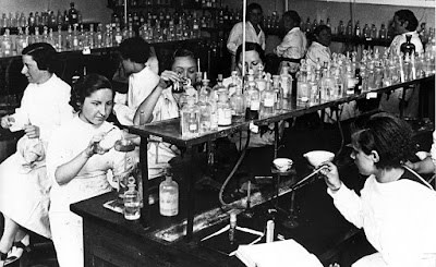 Un grupo de mujeres trabajando en un laboratorio, manipulando frascos y herramientas de laboratorio, durante el periodo de la Residencia de Señoritas.