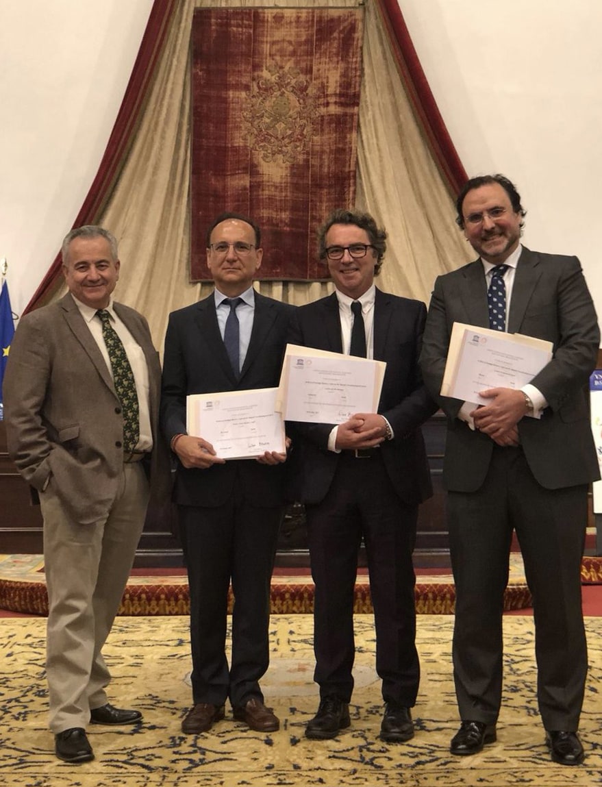 Diploma ceremony recognizing the archive of Santiago Ramon y Cajal and the Spanish School of Neurohistology, with four attendees holding diplomas against a decorative backdrop.