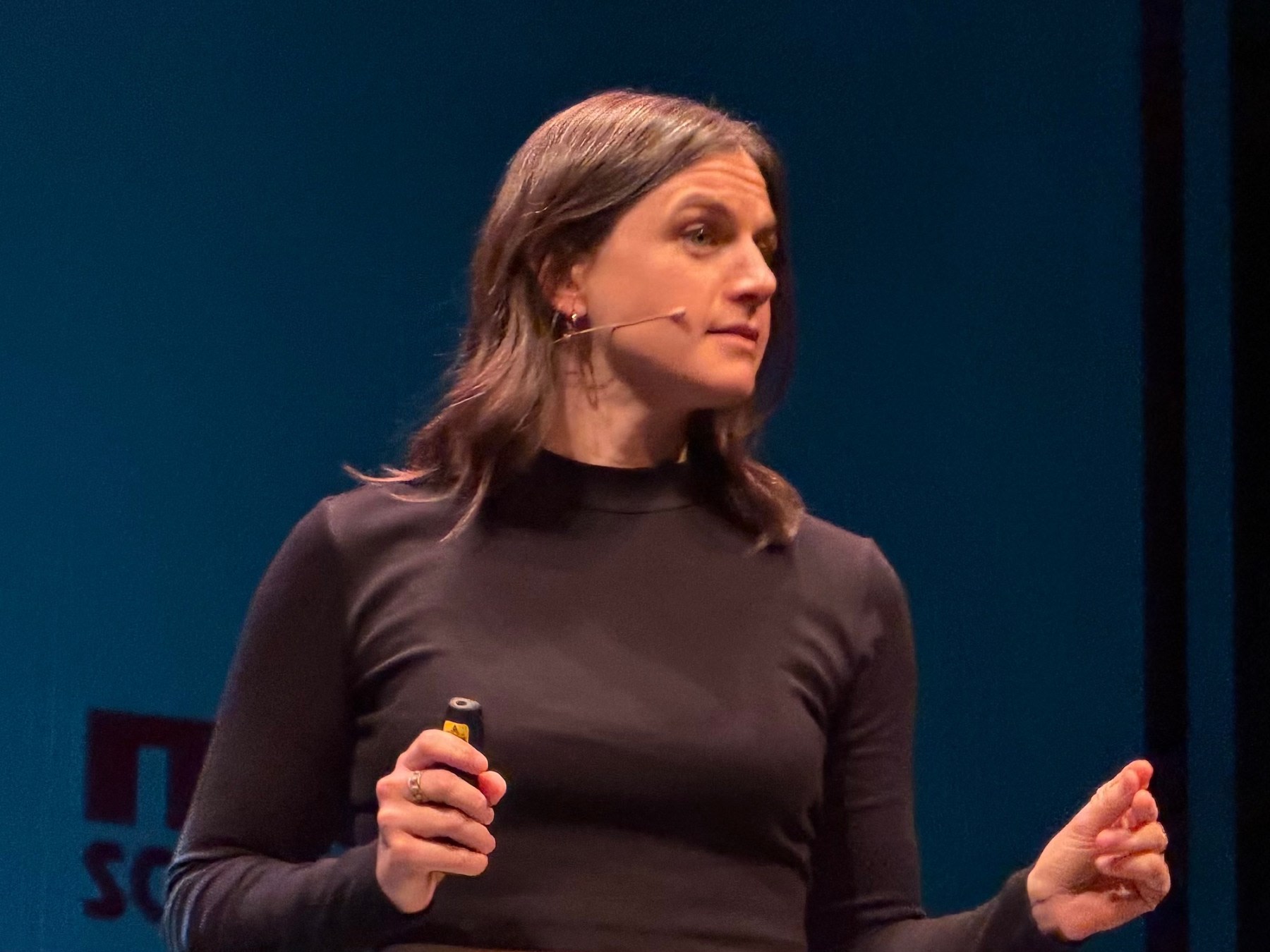 Una ponente en el escenario del Teatro Liceo durante el MUY Science Fest 2025, sosteniendo un dispositivo en su mano y mirando al público.