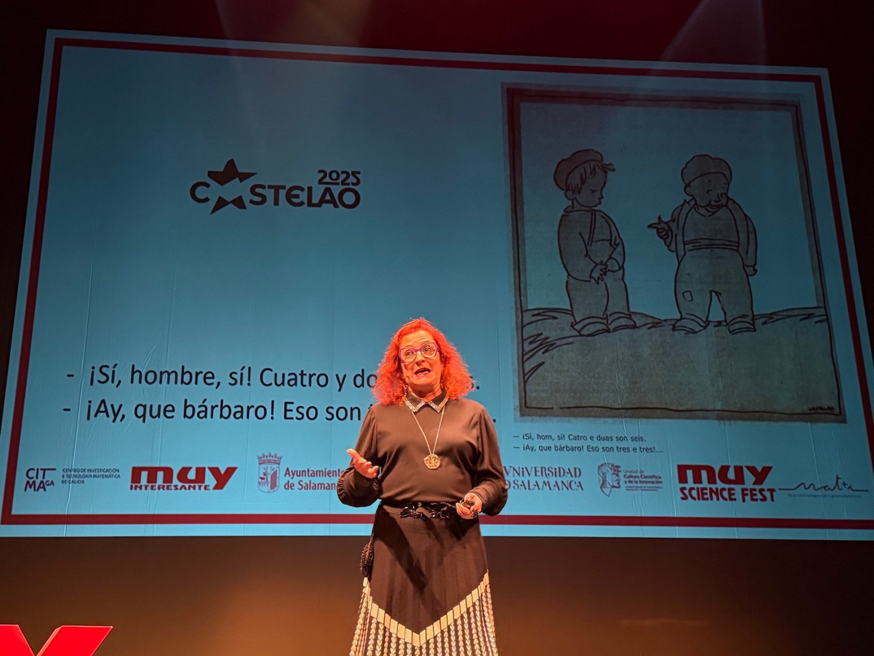Oradora en el MUY Science Fest 2025 en el Teatro Liceo de Salamanca, mostrando una ilustración en la pantalla detrás de ella, mientras discute sobre un tema científico con humor.