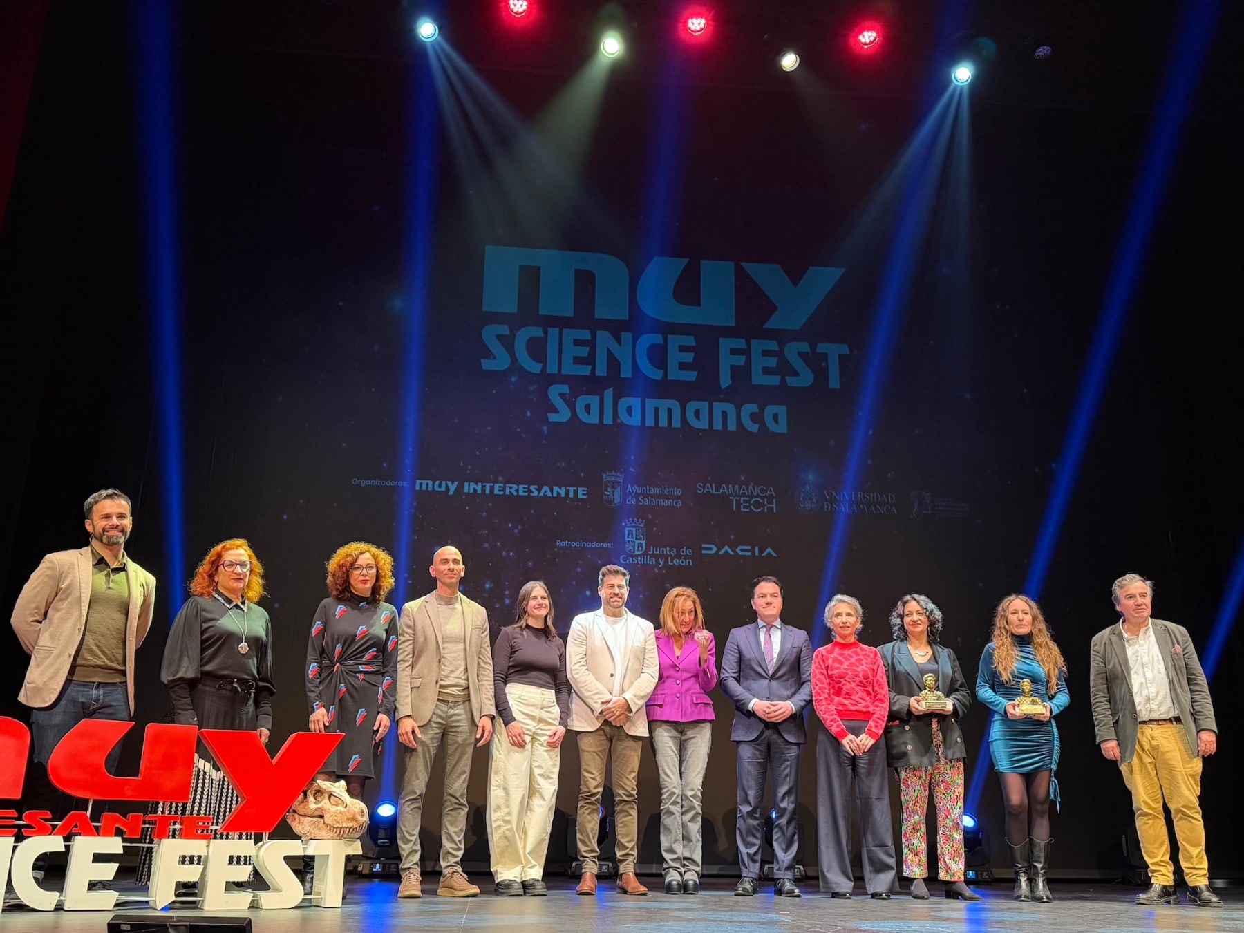 Grupo de ponentes y organizadores posando en el escenario durante el MUY Science Fest en Salamanca, con el logotipo del evento y una decoración temática.