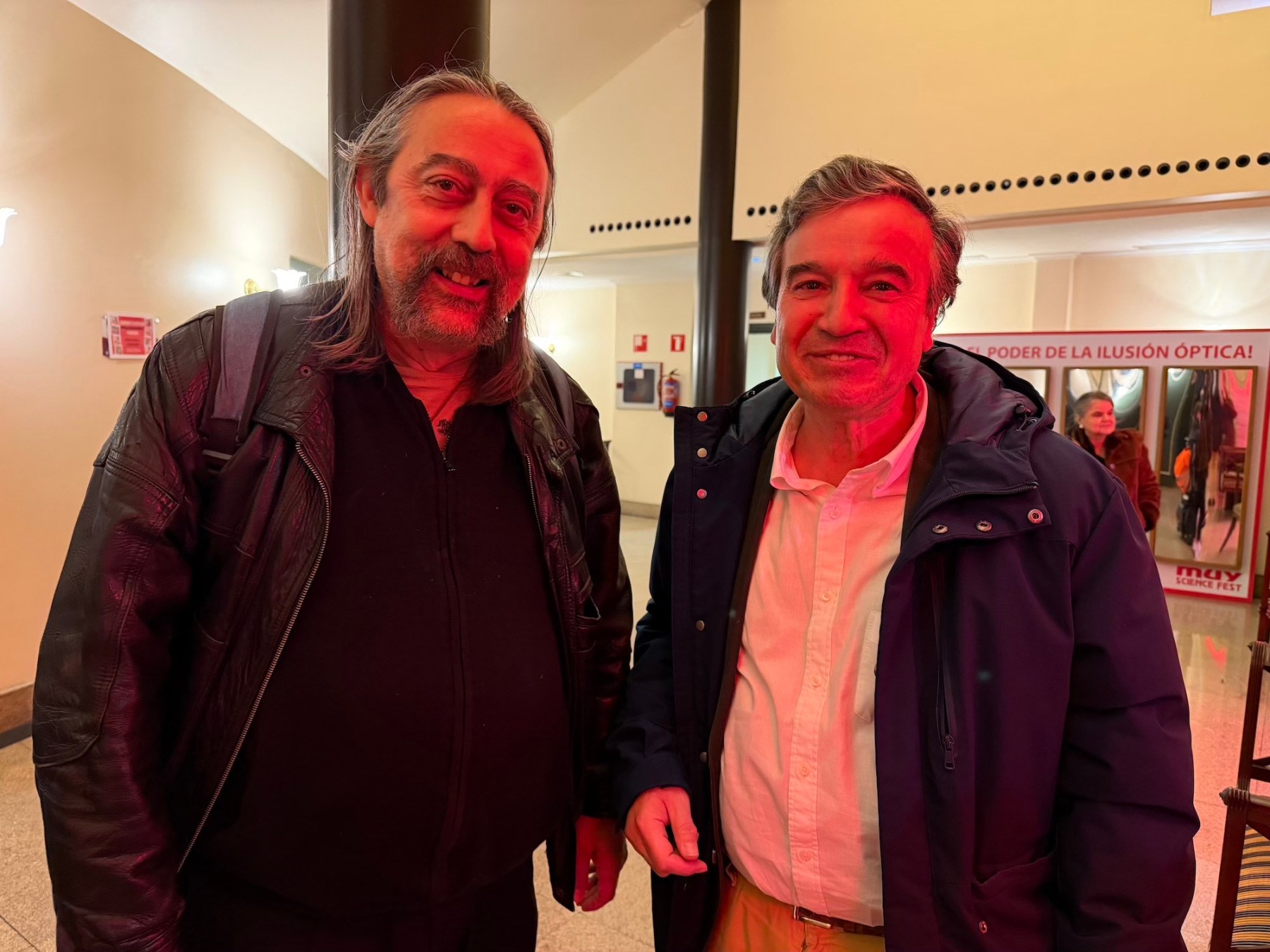 Dos hombres de pie sonriendo en el interior del Teatro Liceo, con una iluminación cálida y ambiente festivo.