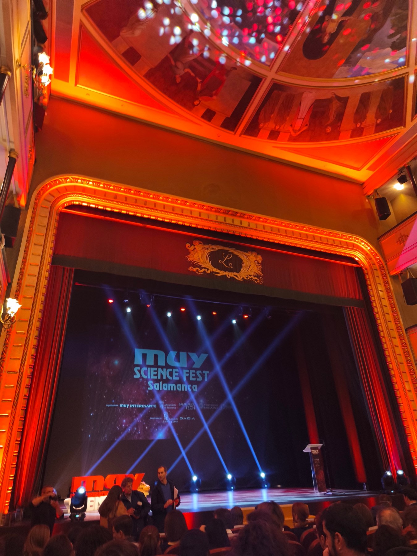 Vista del escenario del MUY Science Fest 2025 en el Teatro Liceo de Salamanca, con iluminación colorida y un telón de fondo que muestra el título del evento.