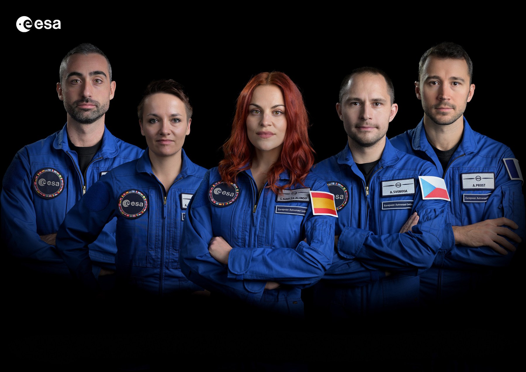 Un grupo de cuatro astronautas de la Agencia Espacial Europea (ESA) posan juntos, vestidos con trajes azules. La astronauta Sara García Alonso se destaca en el centro, mostrando la bandera de España en su uniforme.